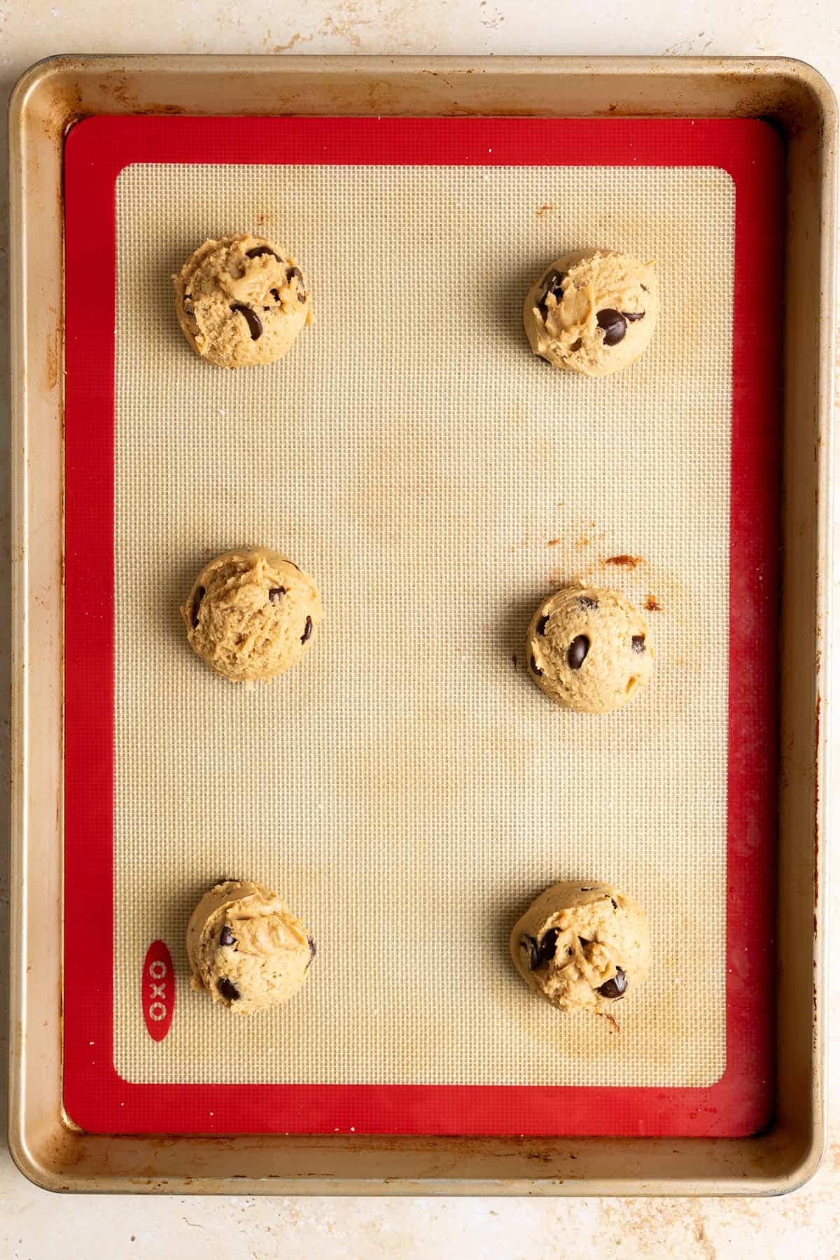 6 cookie dough balls on a baking sheet.
