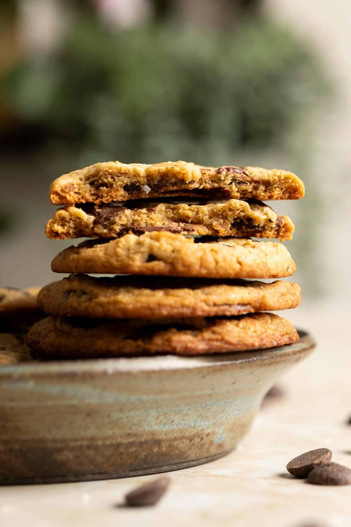 A stack of miso sourdough chocolate chip cookies sitting on a rim of a plate.