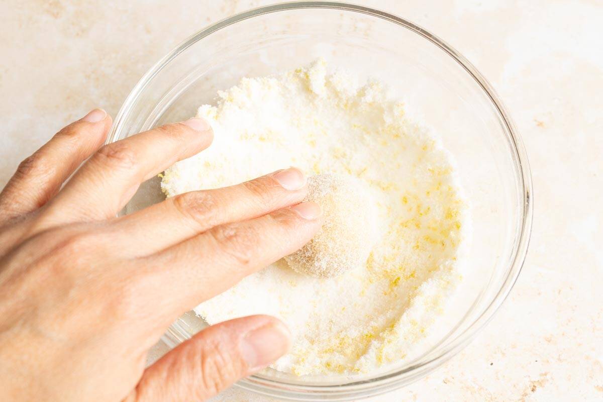 Rolling a dough ball in lemon sugar.
