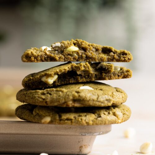 A stack of sourdough matcha cookies resting on the rim of a baking sheet.