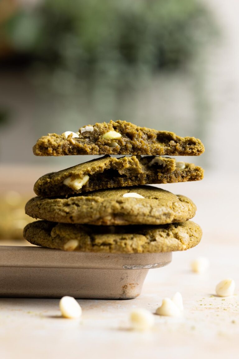 A stack of sourdough matcha cookies resting on the rim of a baking sheet.
