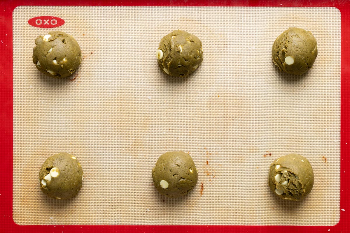 6 sourdough matcha cookie dough balls on a baking sheet.