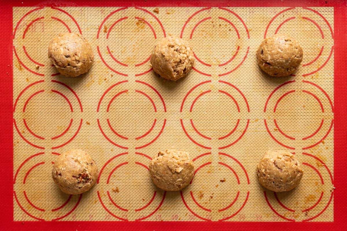 6 pecan oatmeal cookie dough balls on a baking sheet.