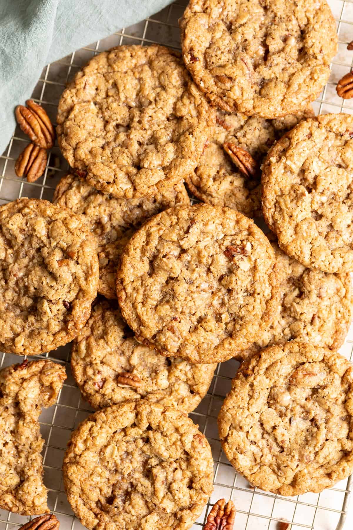 Sourdough oatmeal cookies with pecans and toffee in a pile on a wire rack.