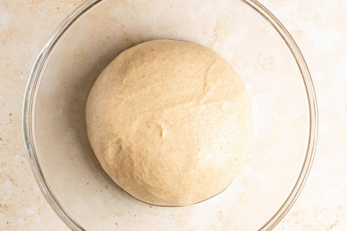 Whole wheat sourdough milk bread dough ball in a glass bowl.