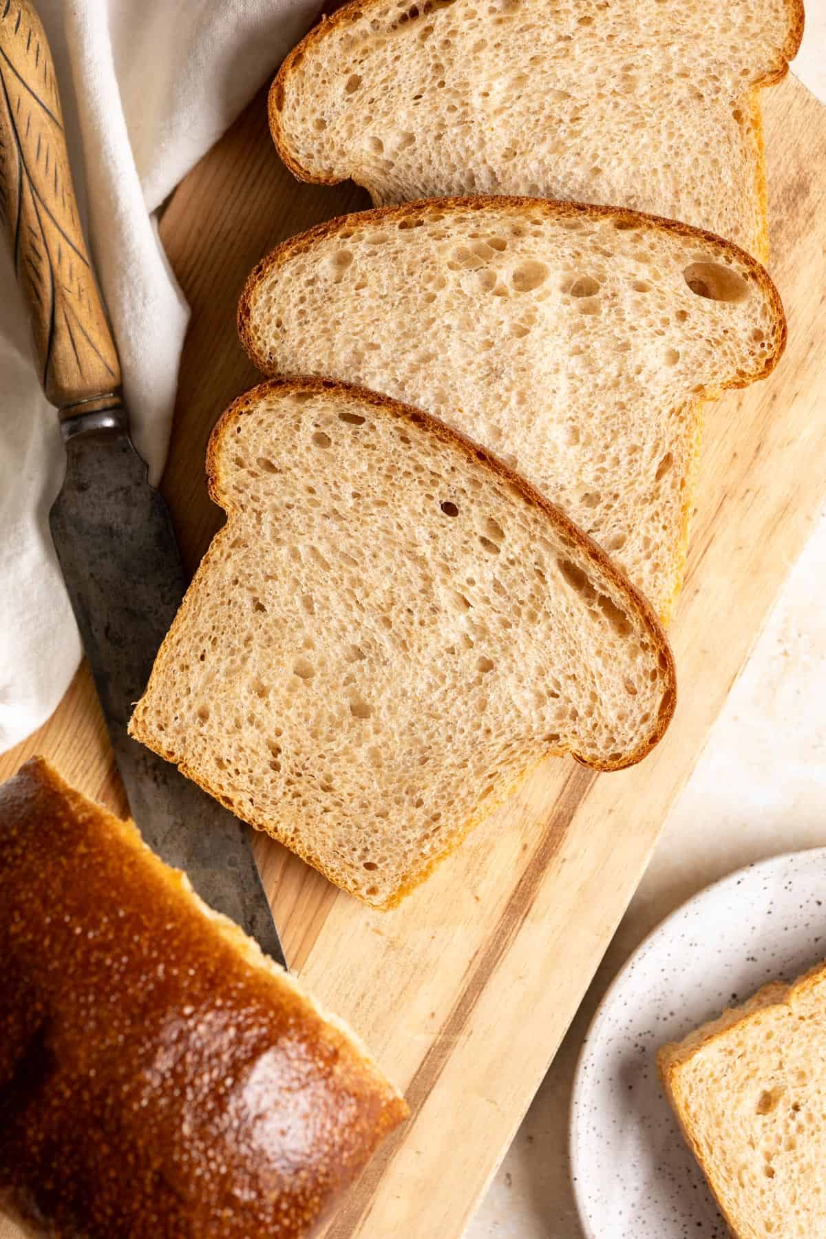 Sliced whole wheat sourdough milk bread on a wooden cutting board.