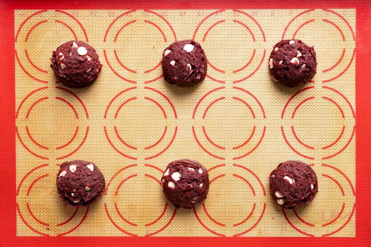 6 sourdough red velvet cookie dough balls on a baking sheet.