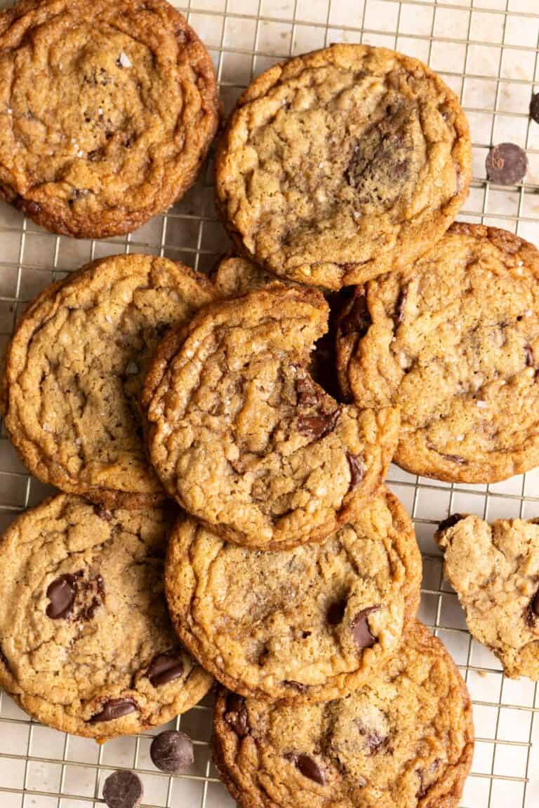 A pile of sourdough chocolate chip cookies with toffee on a wire rack.
