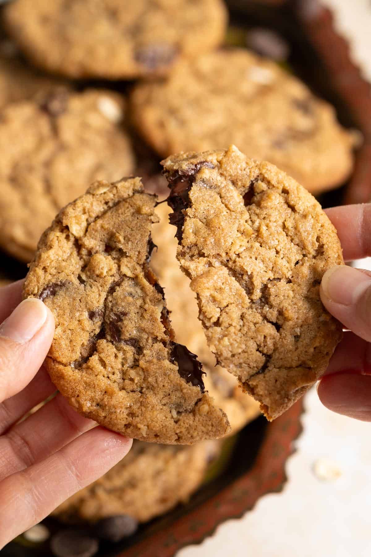 Breaking a chocolate chip sourdough oatmeal cookie in half.