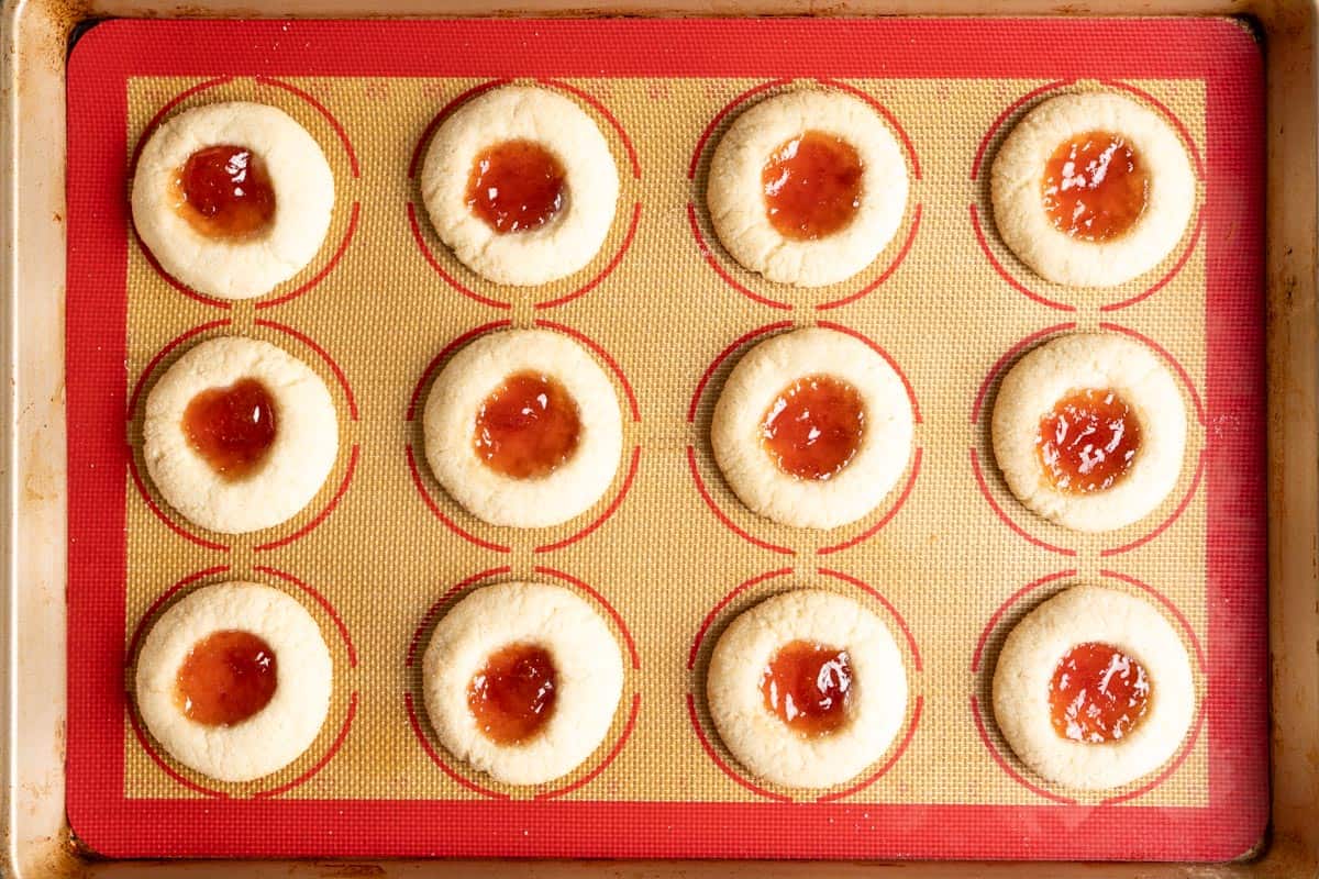 Baked sourdough thumbprint cookies on a baking tray.
