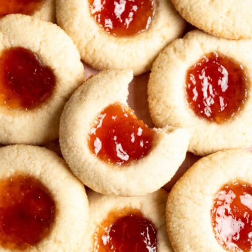 A pile of sourdough thumbprint cookies, one with a bite taken out of it.