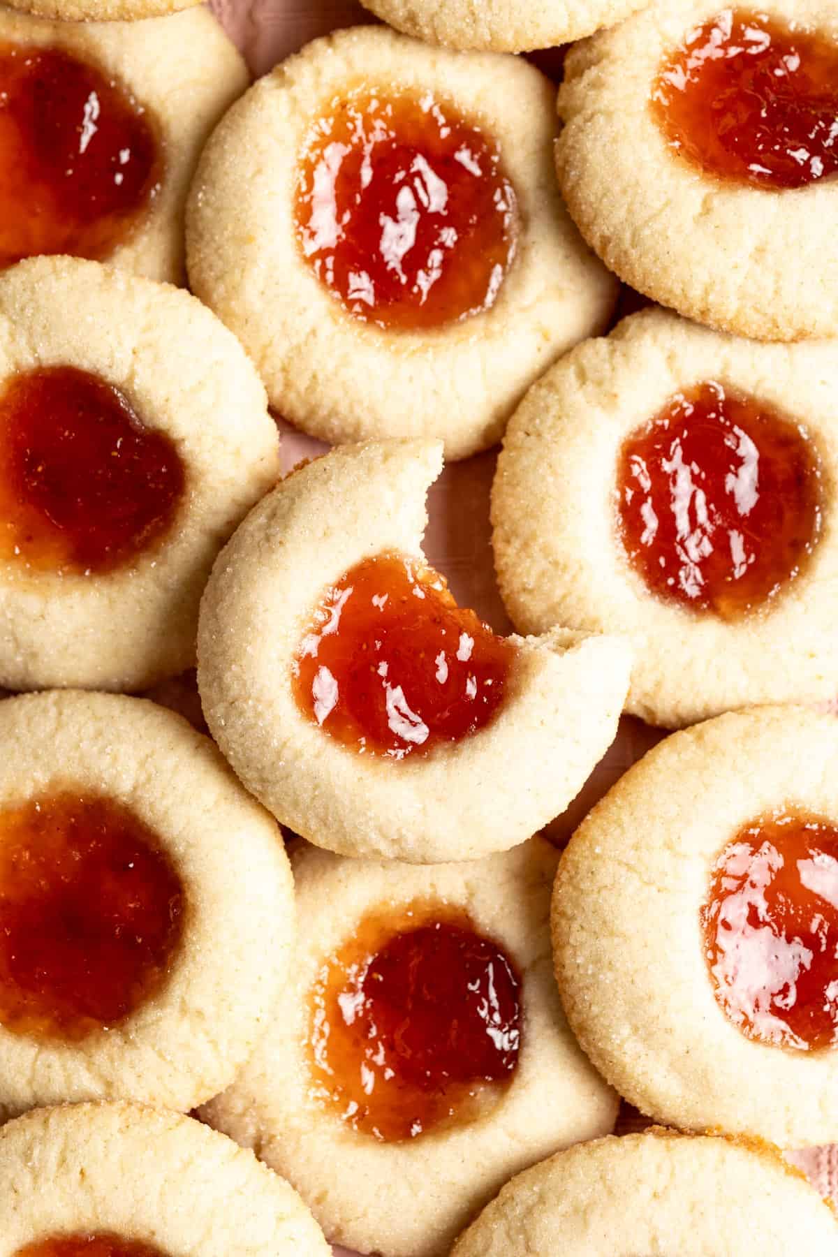 A pile of sourdough thumbprint cookies, one with a bite taken out of it.