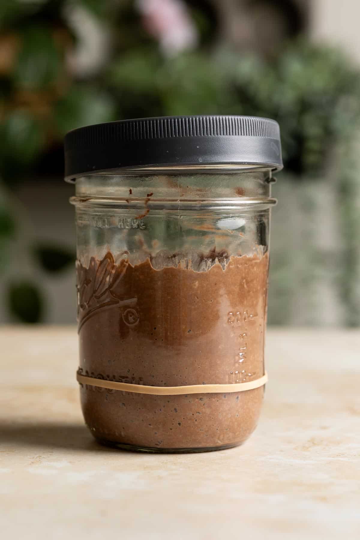 A glass jar with chocolate sourdough starter in it.
