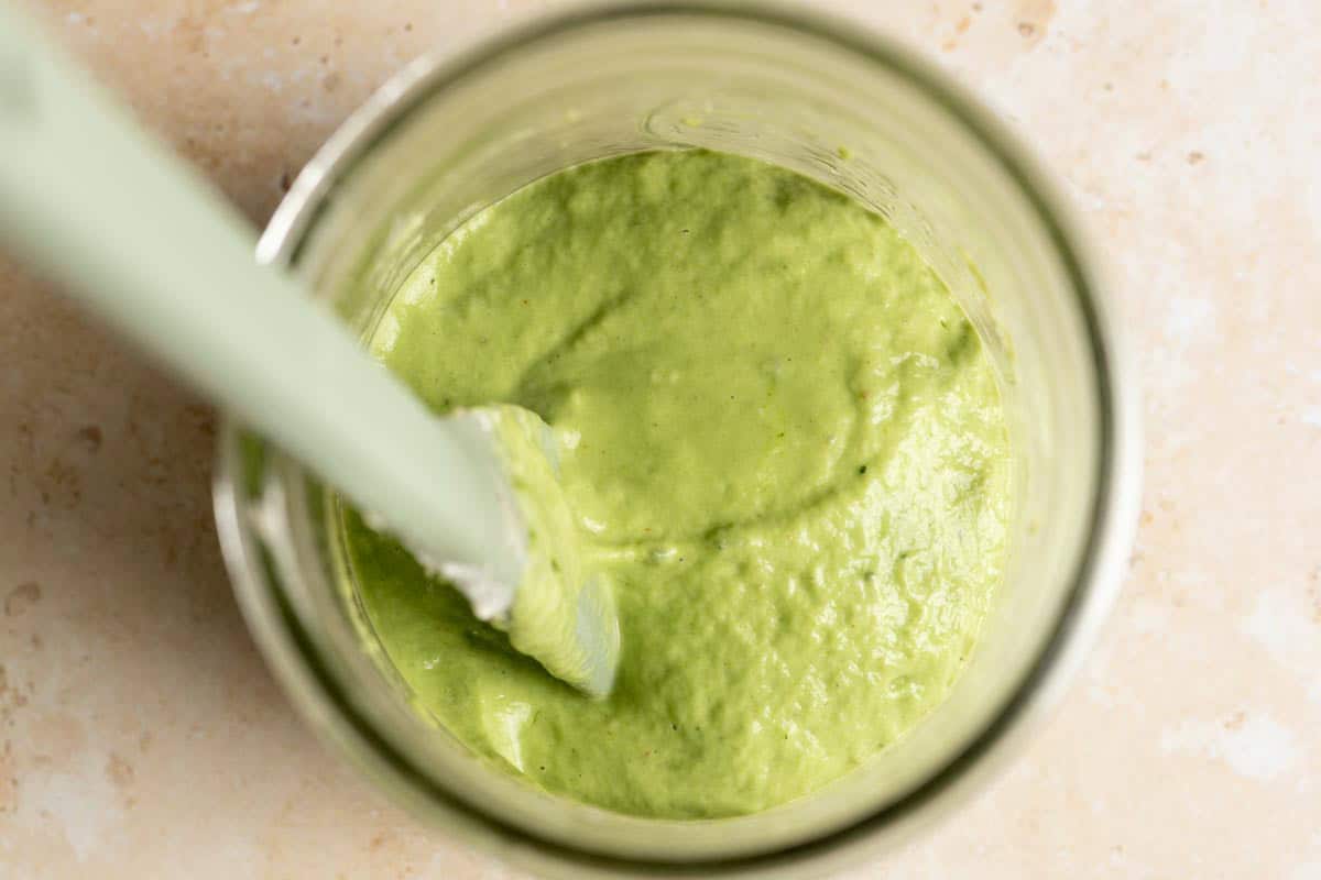 Matcha starter is mixed in a jar with a spatula.