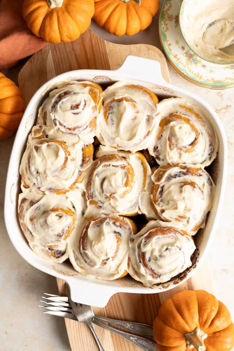 Frosted sourdough pumpkin cinnamon rolls in a square baking pan.