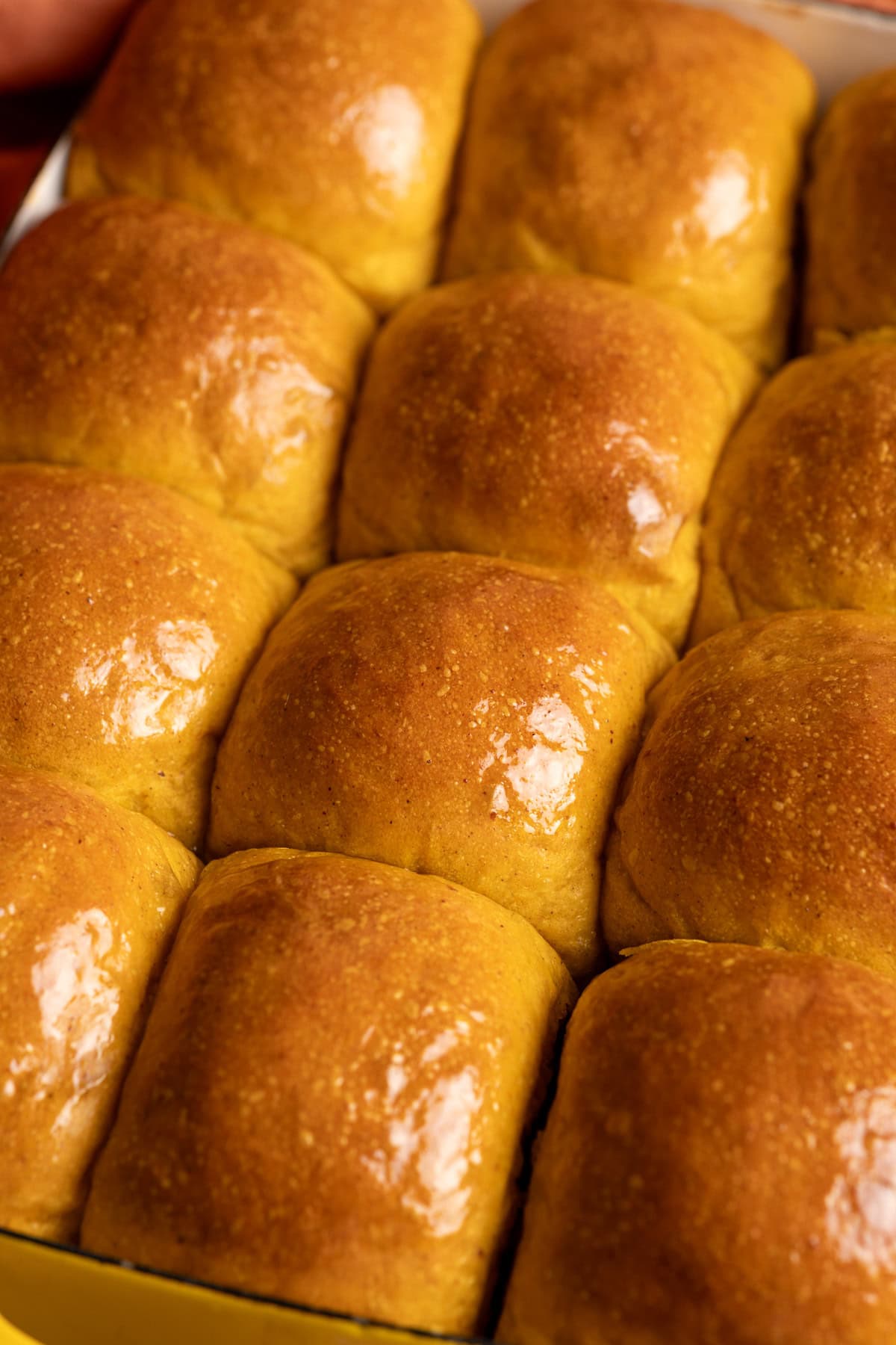 Shiny buttered sourdough pumpkin dinner rolls.