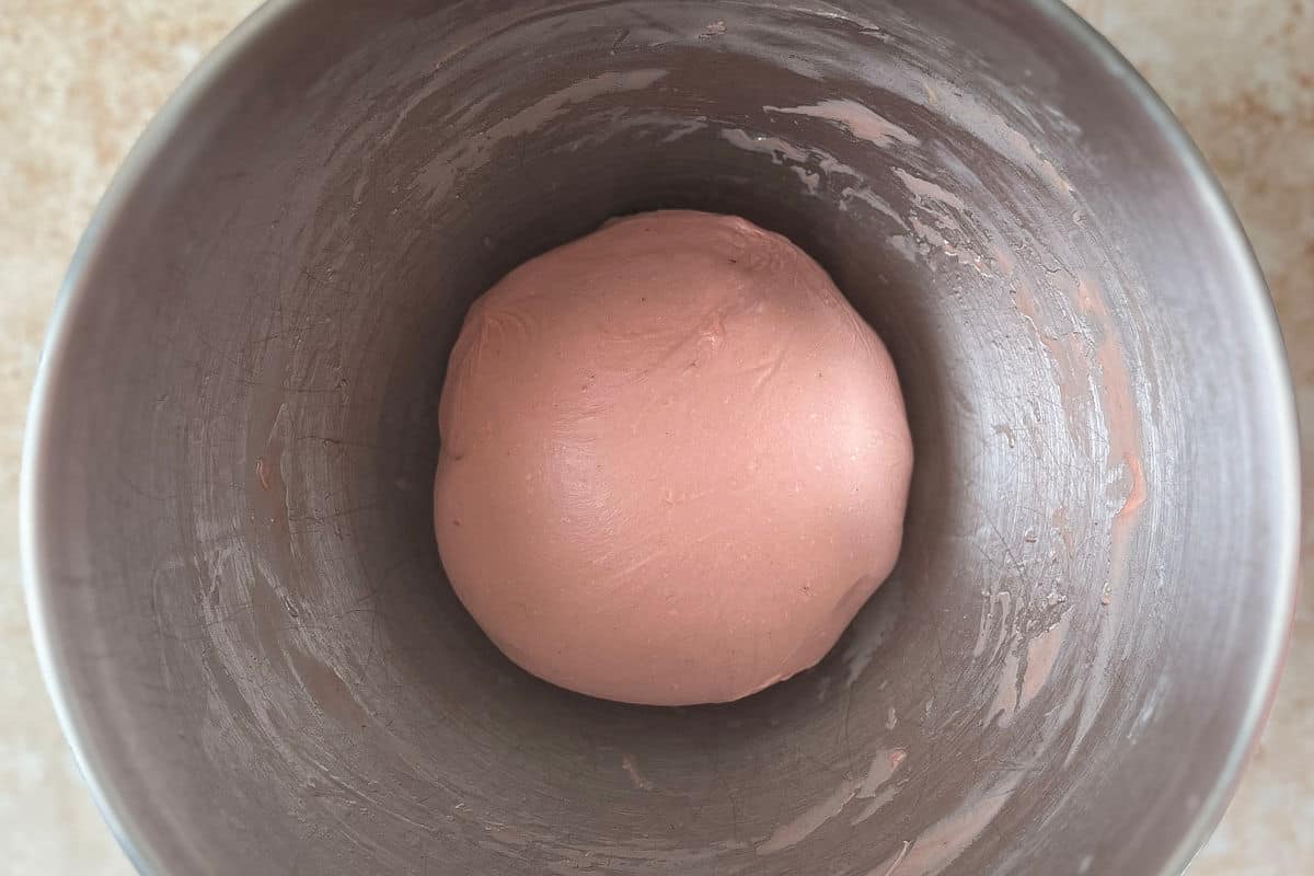 Strawberry milk bread dough ball in a metal bowl.