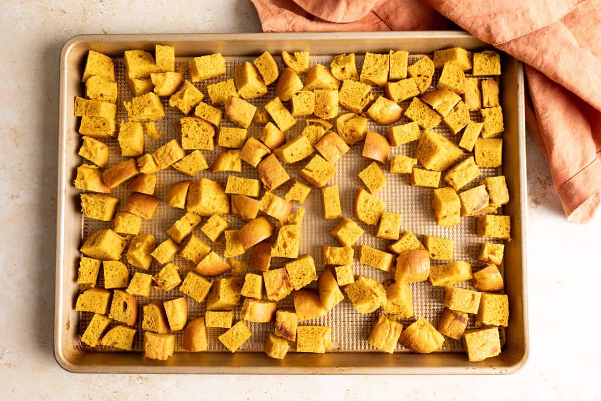 Pumpkin milk bread cubes drying on a baking tray.