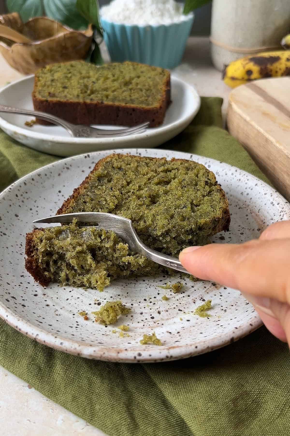 Cutting a slice of matcha black sesame sourdough banana bread on a plate.